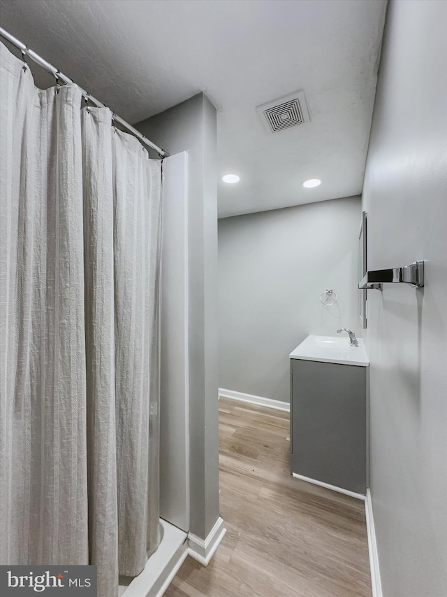 bathroom featuring a shower with shower curtain, hardwood / wood-style floors, and vanity