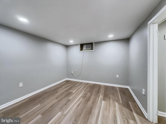 basement with light hardwood / wood-style floors and a wall unit AC