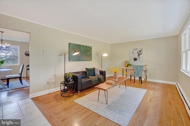 living room with hardwood / wood-style floors, an inviting chandelier, ornamental molding, and a baseboard heating unit