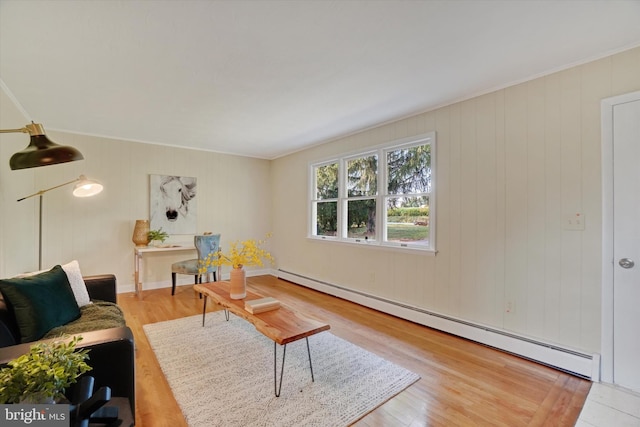 living room with baseboard heating, ornamental molding, and hardwood / wood-style flooring