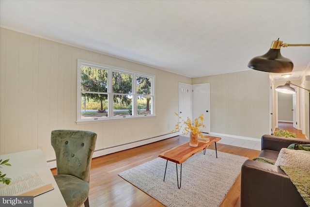 living room with wood walls, light hardwood / wood-style floors, and a baseboard heating unit