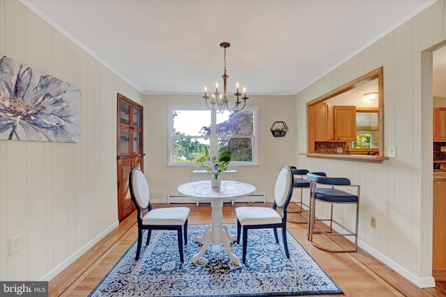 dining area with crown molding, light hardwood / wood-style floors, wood walls, and a notable chandelier