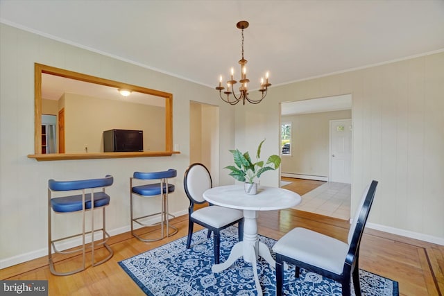 dining area with wood-type flooring, ornamental molding, a baseboard radiator, and a chandelier