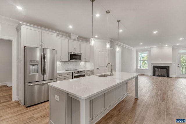 kitchen with appliances with stainless steel finishes, an island with sink, white cabinetry, and sink