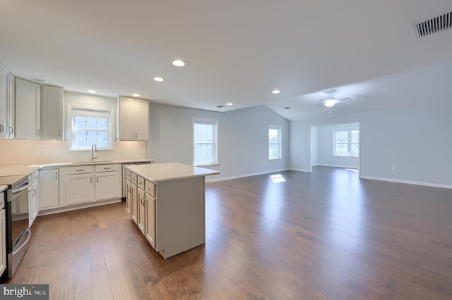 kitchen featuring dark wood-type flooring, sink, electric range, a kitchen island, and white cabinetry