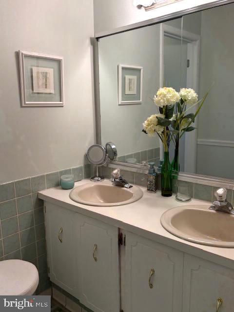 bathroom with vanity, tile walls, and toilet