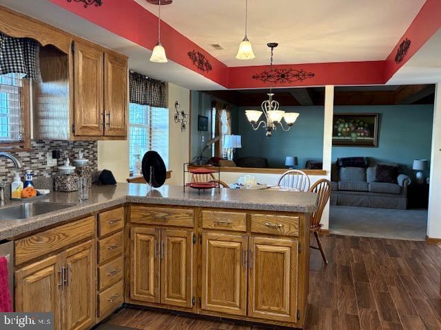 kitchen featuring dark hardwood / wood-style flooring, kitchen peninsula, sink, and hanging light fixtures