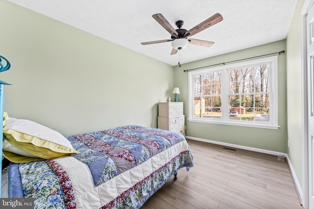 bedroom with ceiling fan, a textured ceiling, and light wood-type flooring