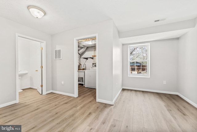 unfurnished bedroom featuring connected bathroom, washer / clothes dryer, and light wood-type flooring