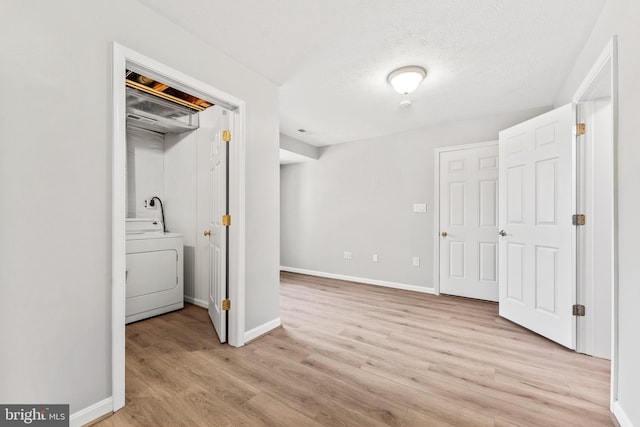 unfurnished bedroom featuring a closet, light wood-type flooring, a textured ceiling, and washer / dryer