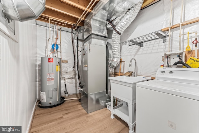 washroom featuring washer / clothes dryer, water heater, and light hardwood / wood-style floors