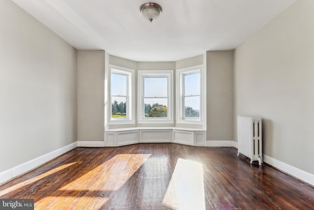 unfurnished room with dark hardwood / wood-style flooring and radiator heating unit