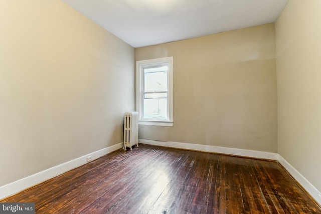 spare room with radiator heating unit and dark hardwood / wood-style floors