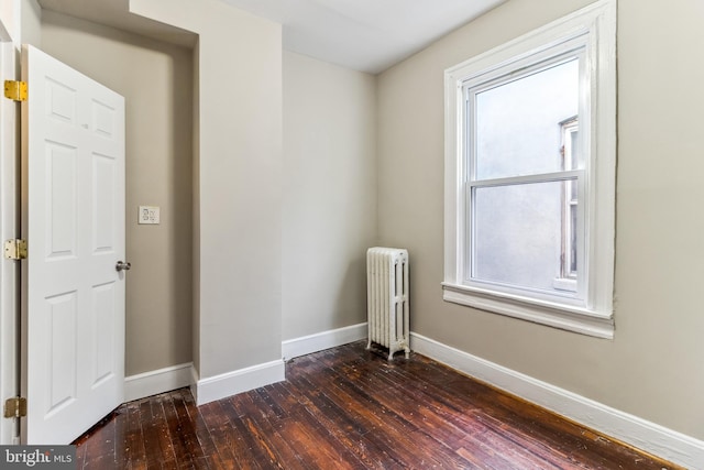 spare room featuring radiator and dark wood-type flooring