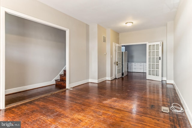 spare room featuring french doors and dark wood-type flooring