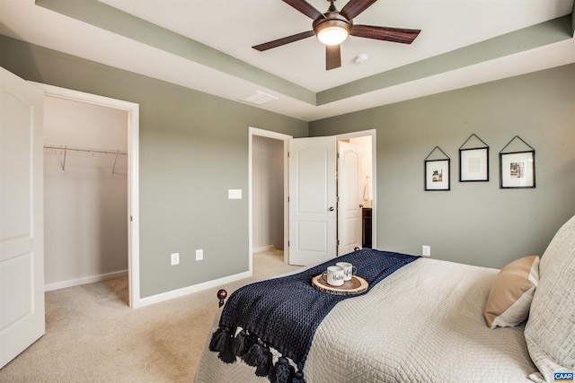 carpeted bedroom with a walk in closet, a closet, and ceiling fan