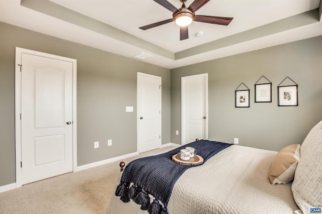 carpeted bedroom with ceiling fan and a tray ceiling