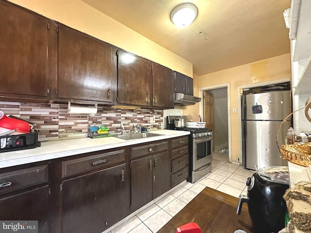 kitchen with sink, light tile patterned flooring, tasteful backsplash, dark brown cabinetry, and appliances with stainless steel finishes