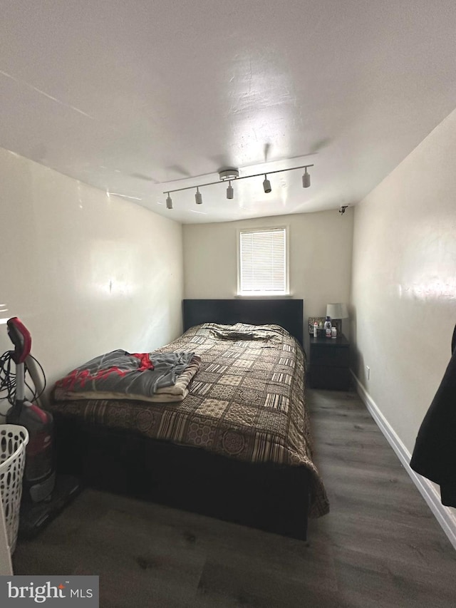 bedroom featuring rail lighting and hardwood / wood-style floors