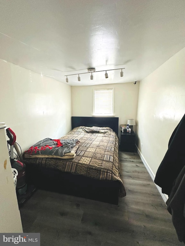 bedroom with hardwood / wood-style flooring and rail lighting