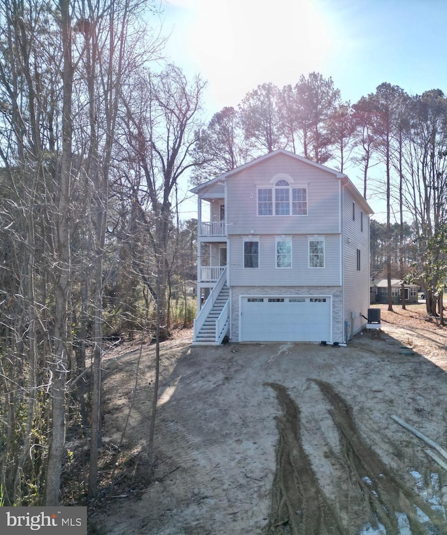 rear view of property featuring central air condition unit, a balcony, and a garage