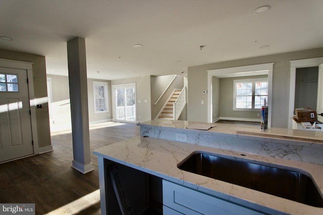 kitchen with light stone counters, dark wood-type flooring, and sink