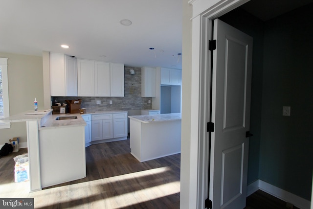 kitchen with white cabinets, dark hardwood / wood-style flooring, backsplash, and kitchen peninsula