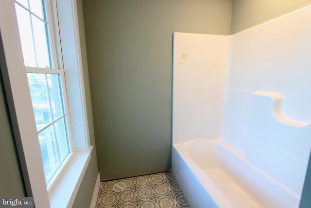 bathroom featuring tile patterned flooring, plenty of natural light, and a bathing tub