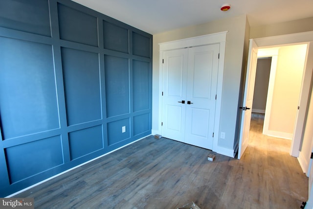 unfurnished bedroom with dark hardwood / wood-style floors and a closet