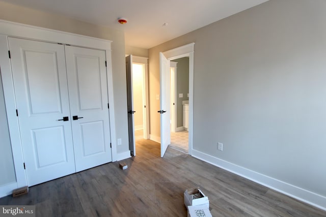 unfurnished bedroom with dark hardwood / wood-style flooring and a closet