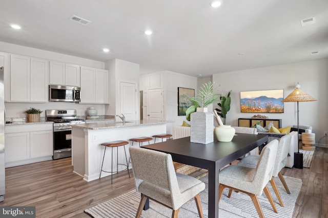 dining space with light hardwood / wood-style flooring and sink