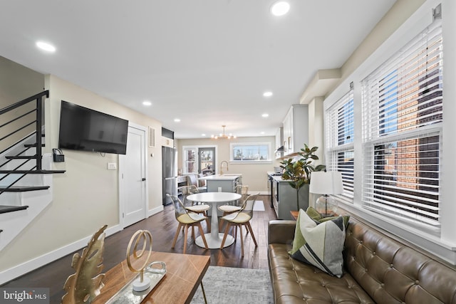 living room featuring an inviting chandelier, dark wood-type flooring, and sink