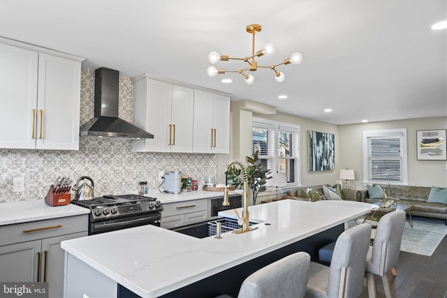 kitchen with wall chimney exhaust hood, high end stove, a chandelier, decorative light fixtures, and decorative backsplash