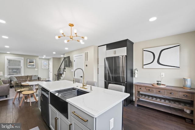 kitchen with pendant lighting, dishwasher, a center island with sink, dark hardwood / wood-style floors, and stainless steel fridge