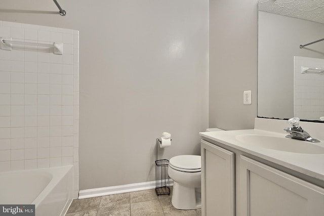 full bathroom with a textured ceiling, vanity, tiled shower / bath combo, and toilet