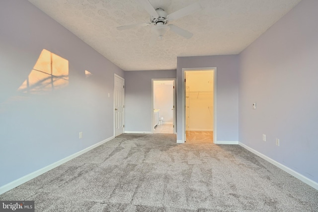 unfurnished bedroom featuring carpet flooring, a spacious closet, ceiling fan, a textured ceiling, and a closet