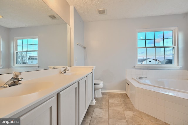 bathroom featuring vanity, tile patterned floors, toilet, a textured ceiling, and tiled bath