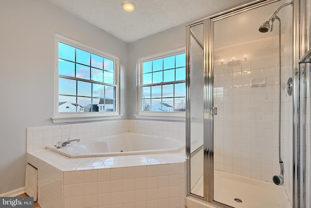 bathroom featuring a textured ceiling and shower with separate bathtub