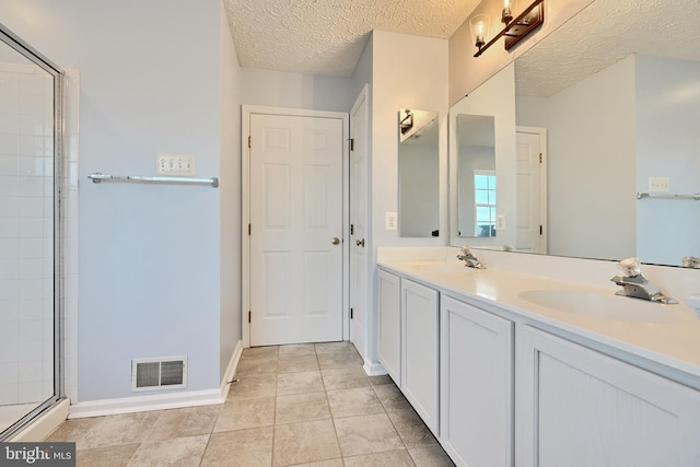 bathroom featuring tile patterned flooring, vanity, an enclosed shower, and a textured ceiling