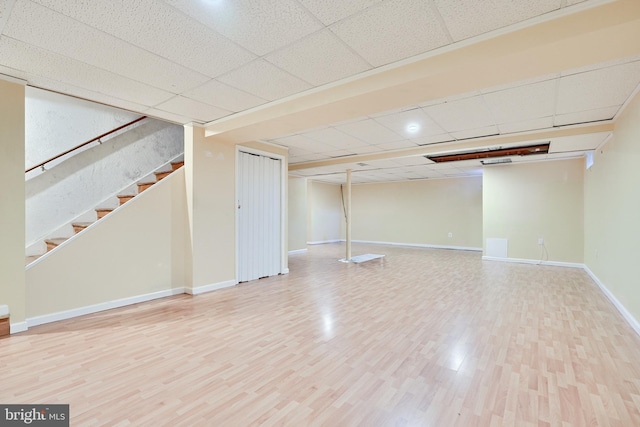 basement with a paneled ceiling and hardwood / wood-style flooring