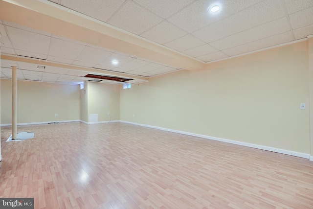 basement with a paneled ceiling and light hardwood / wood-style floors