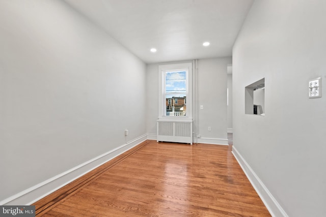 unfurnished room featuring radiator and light wood-type flooring