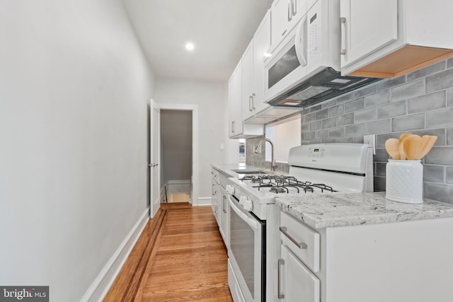 kitchen featuring white appliances, sink, light hardwood / wood-style floors, light stone counters, and white cabinetry