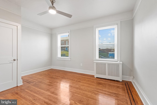 empty room with ceiling fan, light hardwood / wood-style floors, and radiator heating unit