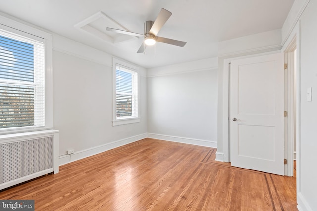 empty room with ceiling fan, radiator heating unit, and light hardwood / wood-style flooring