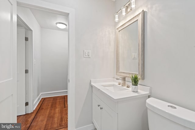 bathroom with hardwood / wood-style floors, vanity, and toilet