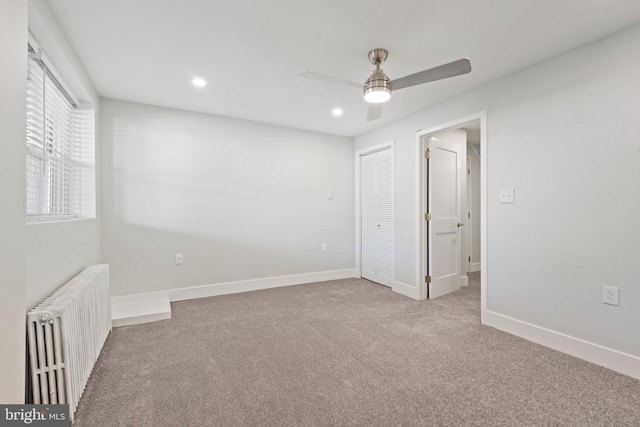 unfurnished bedroom with light carpet, a closet, radiator, and ceiling fan