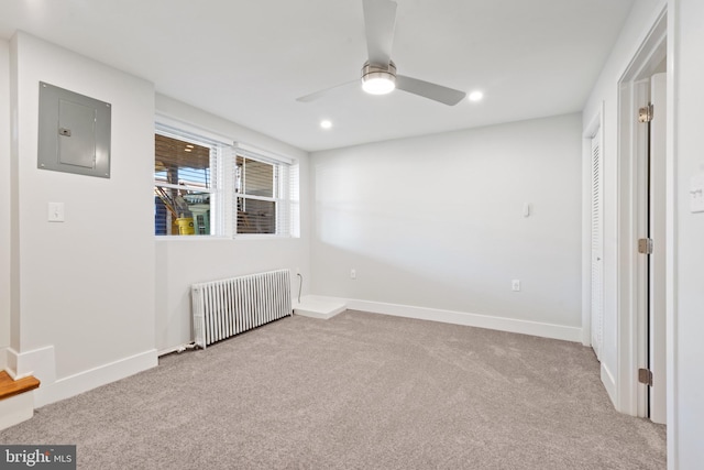 carpeted spare room with radiator, ceiling fan, and electric panel