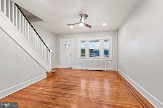 foyer entrance featuring hardwood / wood-style floors, ceiling fan, and radiator heating unit