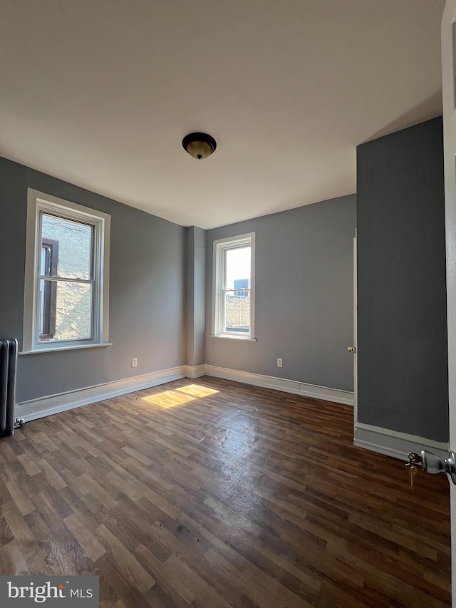 unfurnished room with radiator and dark hardwood / wood-style flooring